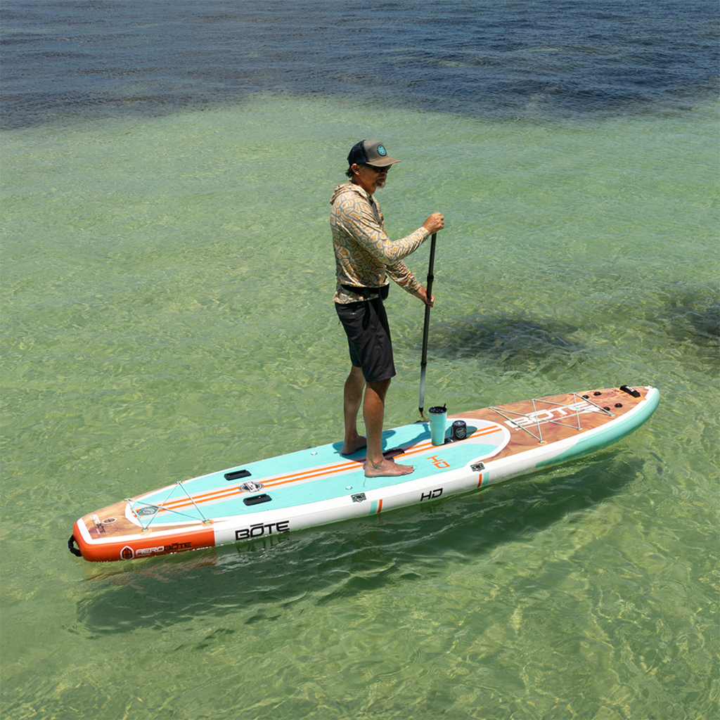 Man paddleboarding on HD Aero in shallow clear water with cup holder attached.