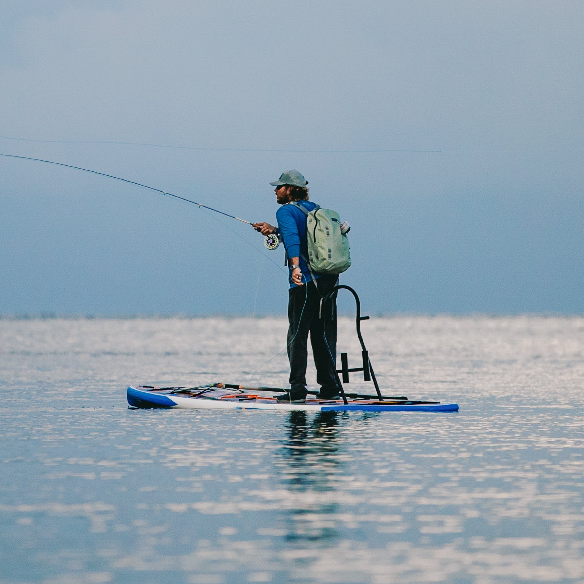 A guy fishing on a HD 12′ Fischer Topwater Paddle Board