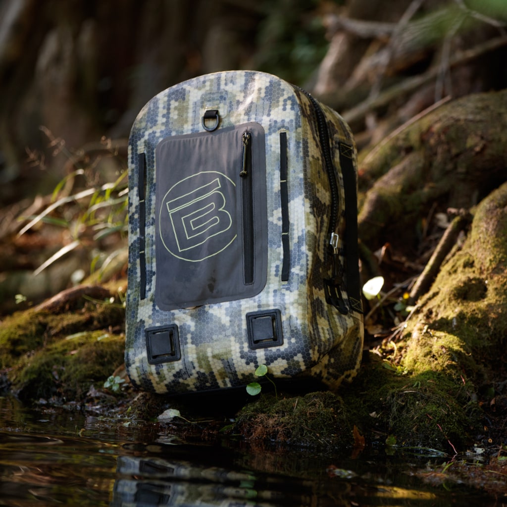 Verge Camo Highwater Backpack sitting at the edge of some water in