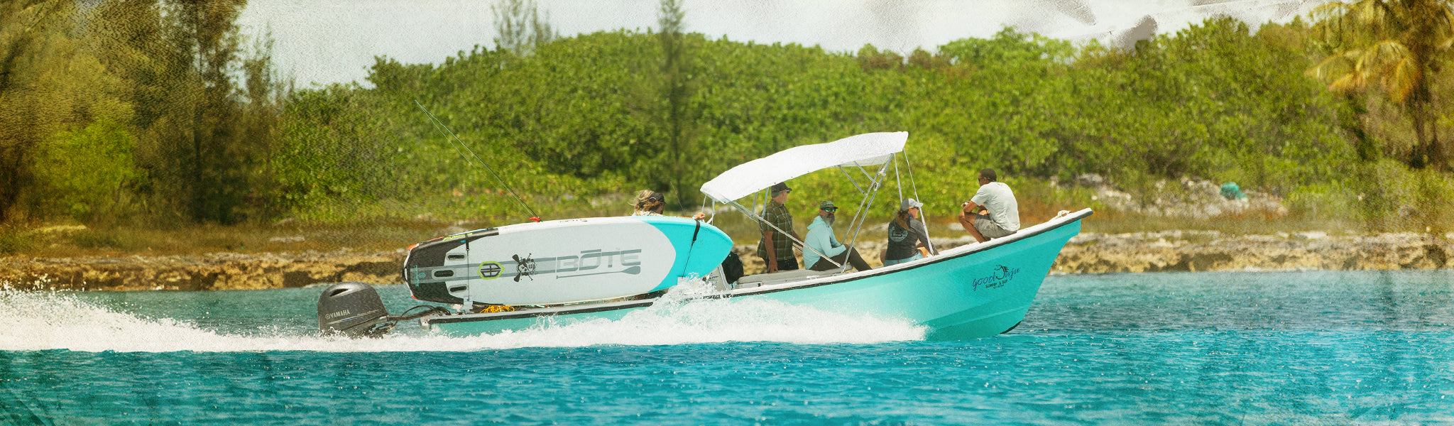 Aerial view of paddle boarders floating together on dark blue lake surrounded by trees.