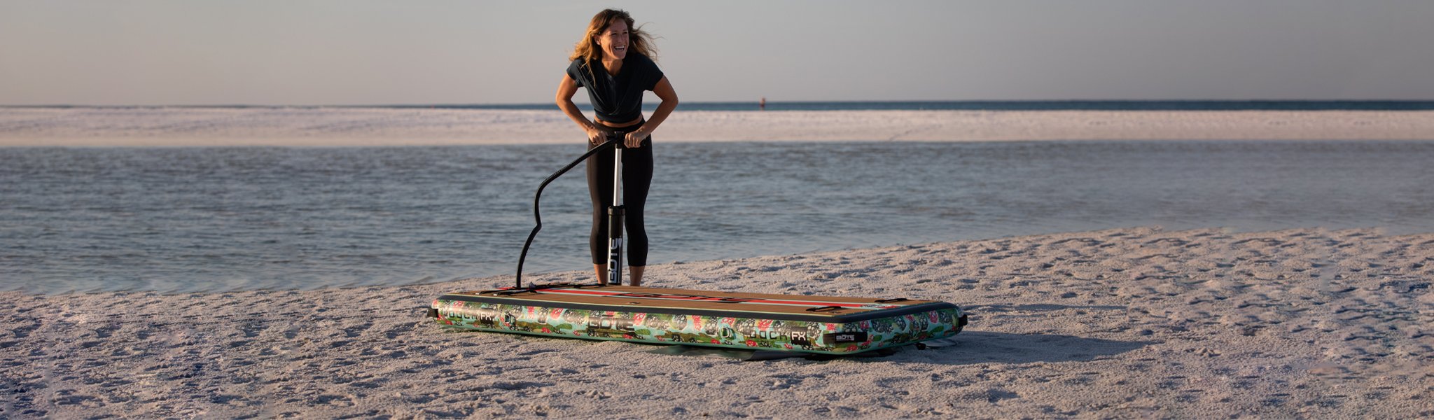 Woman smiling while inflating an inflatable dock on a sandy beach.