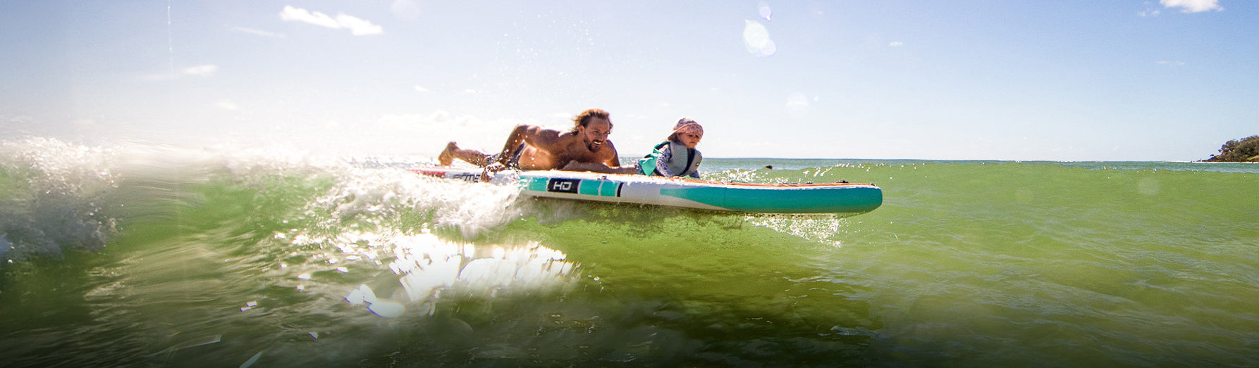 A father and his kid laying down on an inflatable paddle board