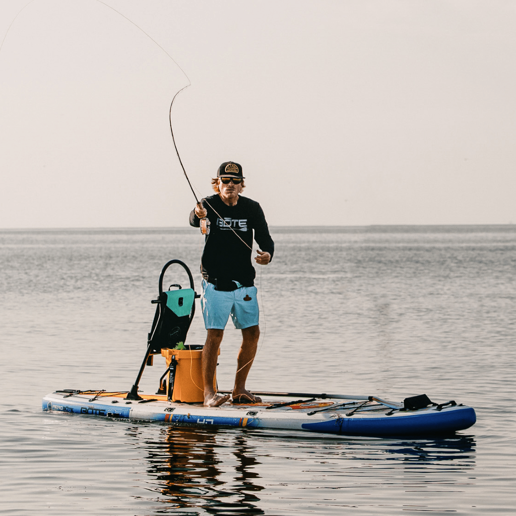 A guy fishing on a HD Aero 11′6″ Fischer Topwater Inflatable Paddle Board