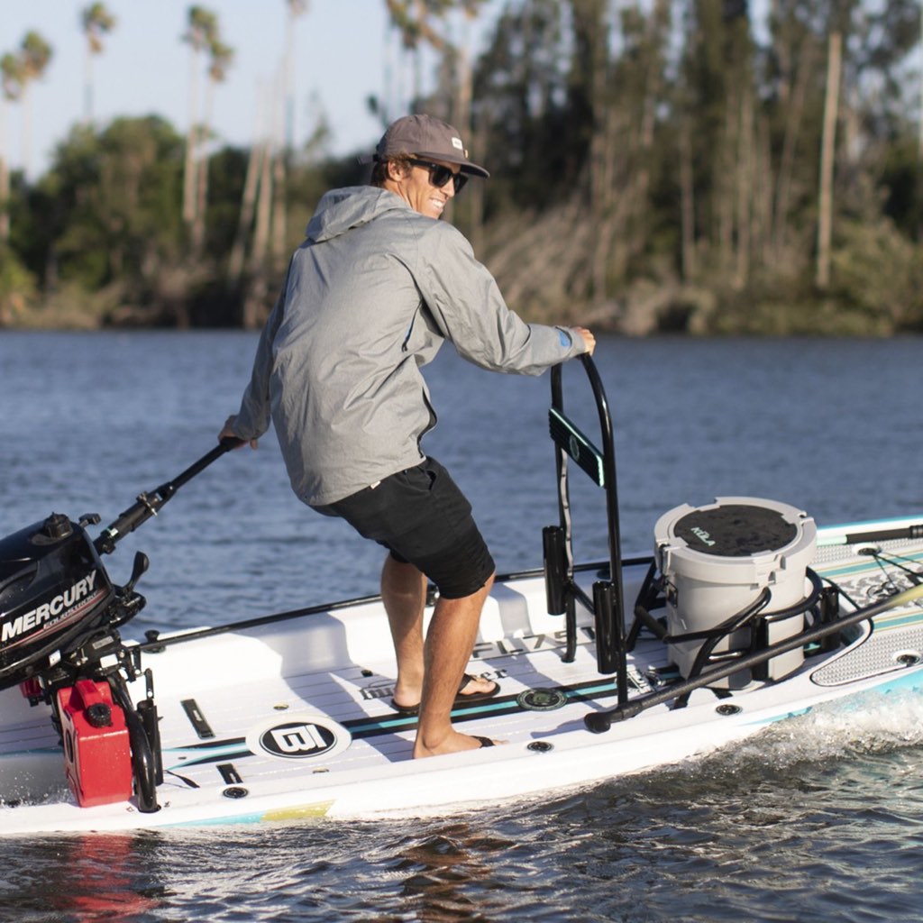 Man steering paddle board with mounted Grab Rac Black and outboard motor on the water.