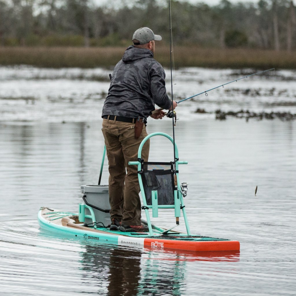 Lifestyle image of Tackle Rac Seafoam on paddle board while man stands and fishes.