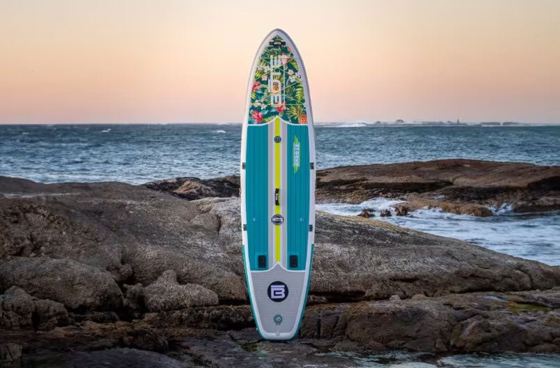 Paddleboard on rocks with a sunset over the ocean